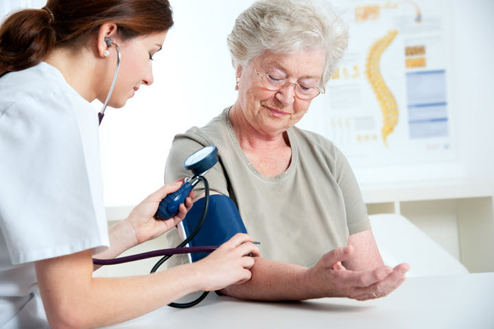 medical professional taking the blood pressure of a senior woman